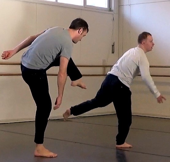 Zwei in Alter und Grösse unterschiedliche Männer tanzen nebeneinander.Sie balancieren auf einem Bein