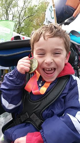Il s'agit de la photo d'Arno, enfant de 8 ans vivant avec une paralysie cérébrale, qui présente la médaille qu'il a reçue au terme des 10km de Lausanne en 2016. Nous pouvons lire la fierté sur son visage.
